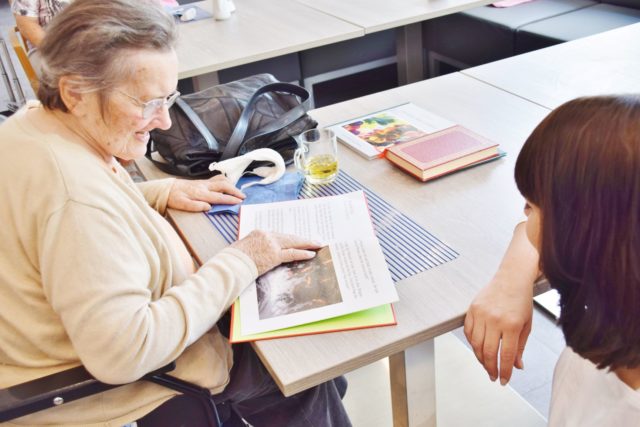 Tagespflege Seniorin und Pflegerin lesen Buch