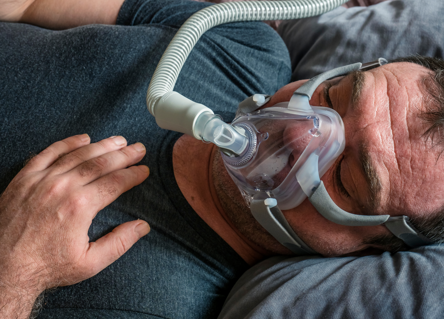Ausserklinische Intensivpflege_Mann Bett Beatmung_beruhigende Hand auf Brust